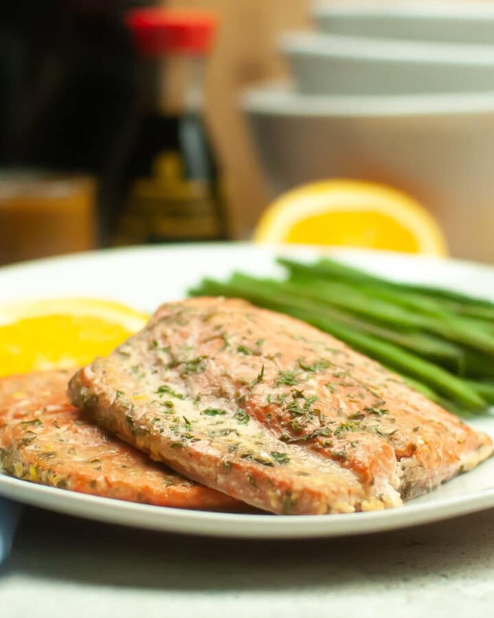 Fresh air fryer salmon fillet with an orange sauce on a white dinner plate.