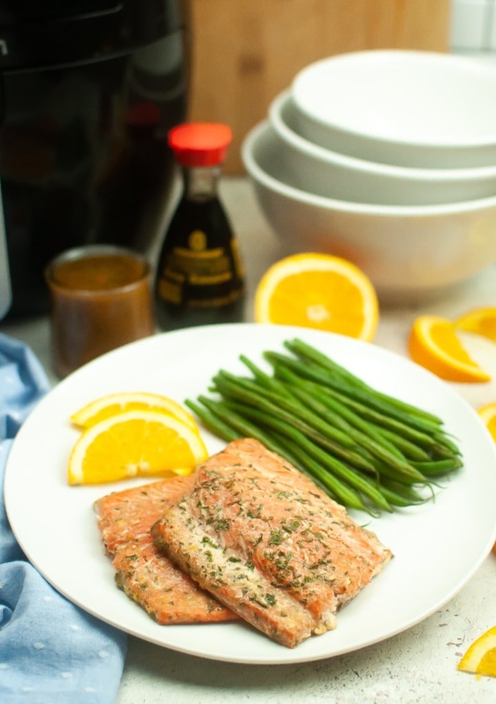 Fresh salmon fillet on a white dinner plate with green beans. 
