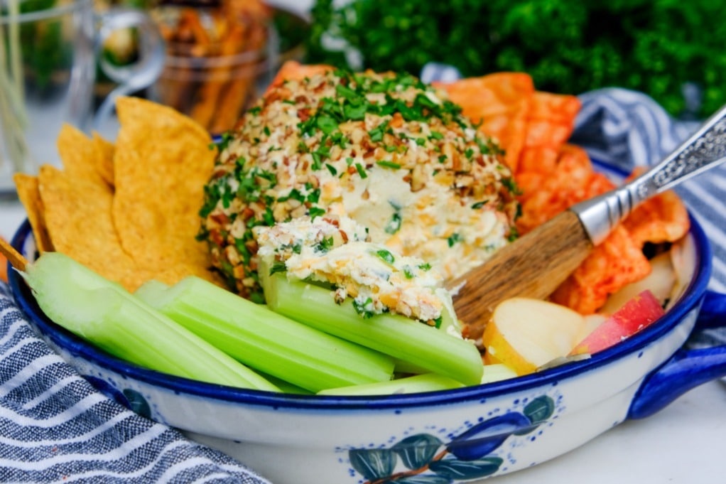 An appetizer plate filled with a a cheese ball and side ingredients to eat the the cheeeball.