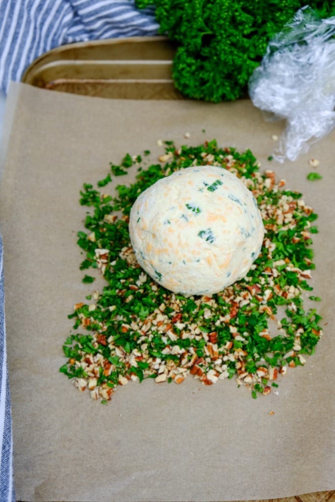 Low carb cheese ball getting ready to roll in mix and parsley mix. 