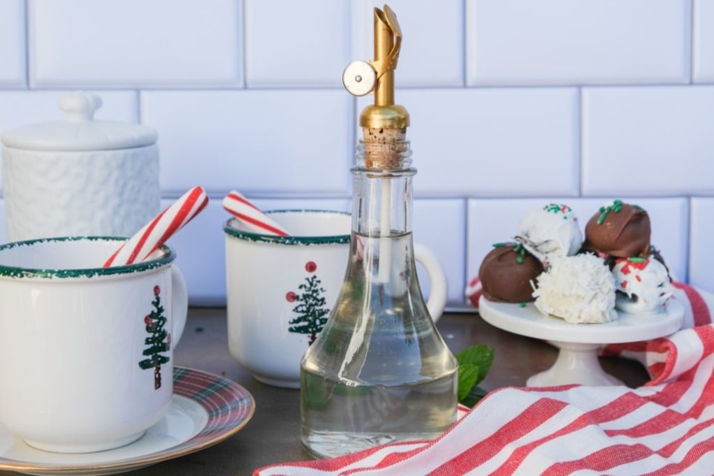 A glass jar with a pour stop filled with peppermint syrup. 