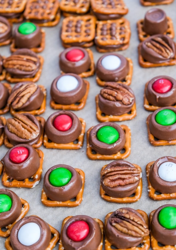 Rolo pretzel bites decorated with m&m candy and pecans cooling after being in the oven. 