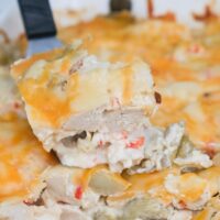 A spatula lifting up a slice of chicken artichoke casserole.