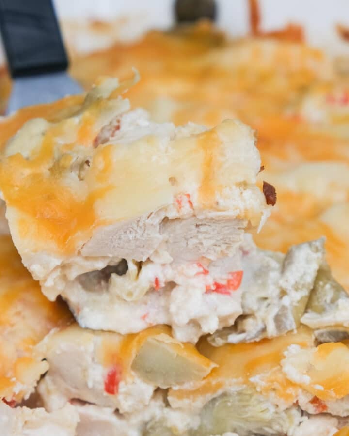 A spatula lifting up a slice of chicken artichoke casserole.