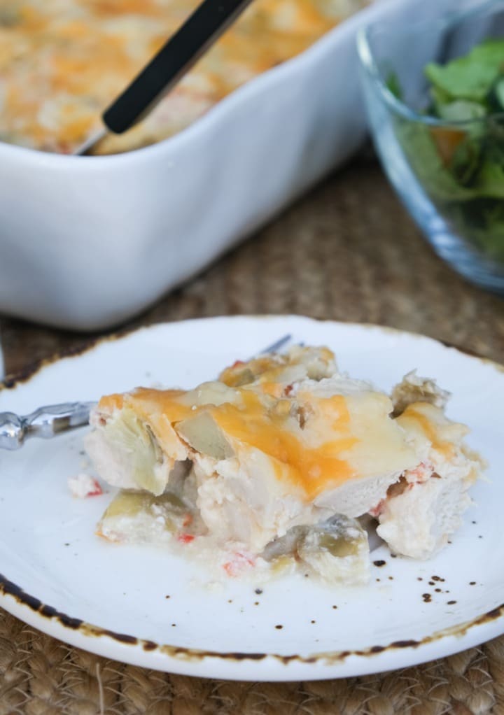 Slice of a chicken casserole on a white plate with a tan rim. 