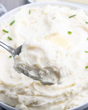 A spoonful of mashed potatoes in a white serving bowl.