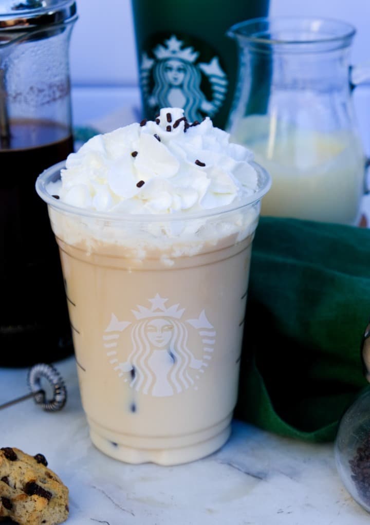 Iced copycat Starbucks white chocolate mocha in a clear Starbucks cup topped with whipped cream. 