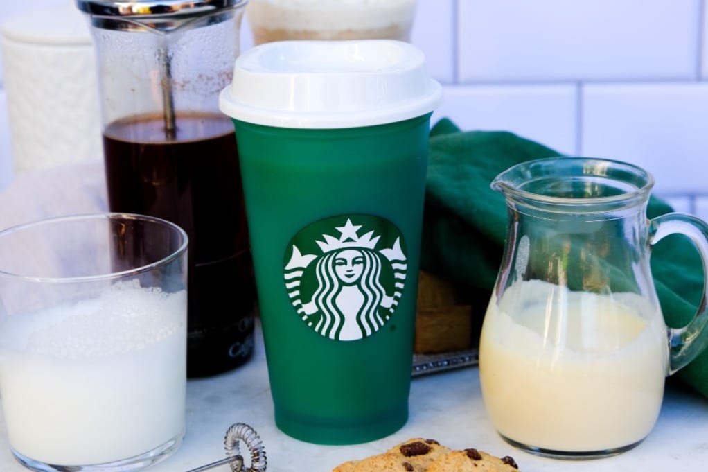 Starbucks green plastic tumbler with white chocolate syrup on the side. 