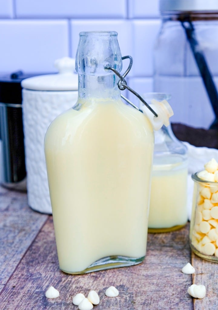 White chocolate syrup in a clear jar with with chocolate chips in a small jar on the side. 