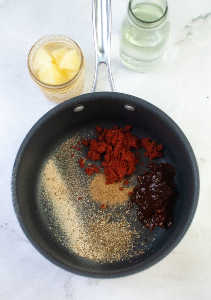 Spices and chipotle in a saucepan before adding pineapple juice to simmer. 