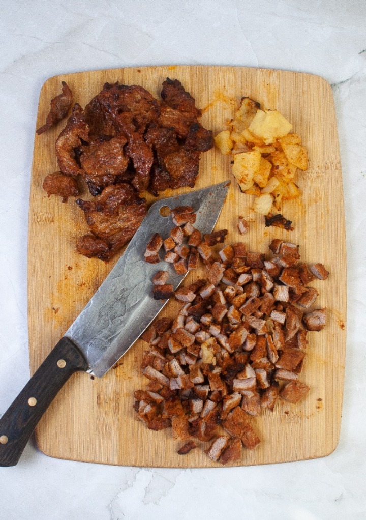 Diced cooked pork on a cutting board for tacos. 