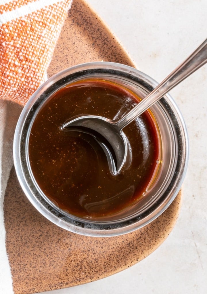 Top view of caramel sauce in a glass jar with a spoon. 