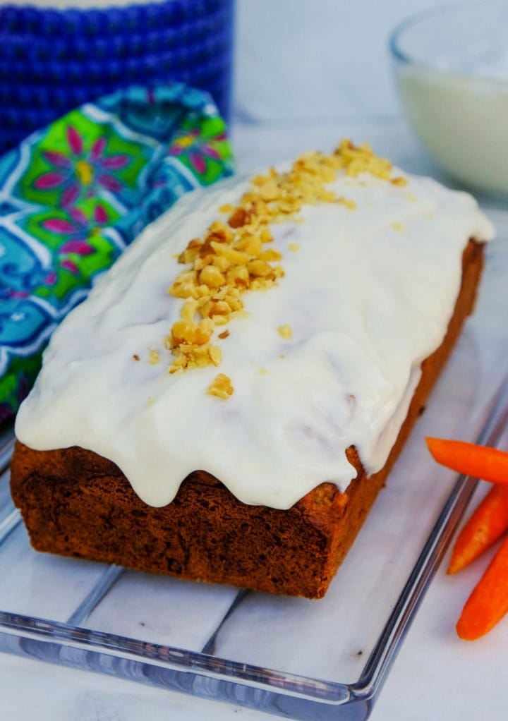 Carrot cake loaf with frosting and sprinkle of chopped nuts. 