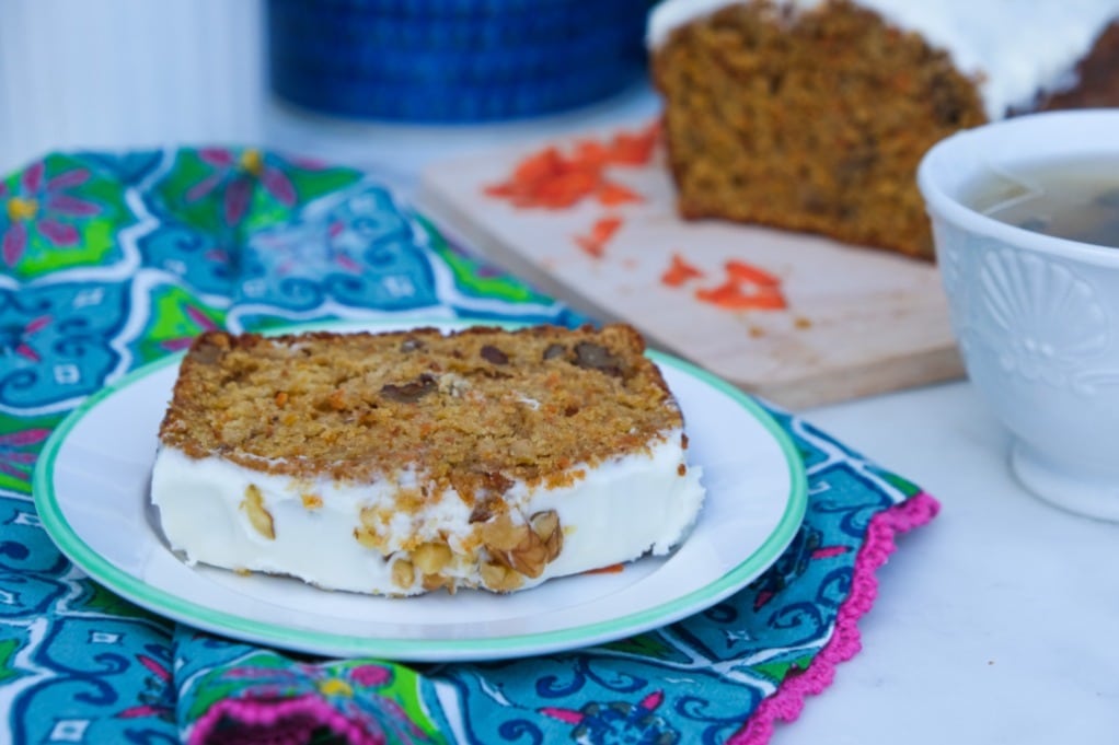 A slice of carrot cake bread on a white plate with a green rim. 