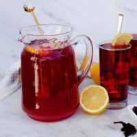 Hibiscus lemonade in a glass pitcher with glasses filled with lemonade ready to drink.