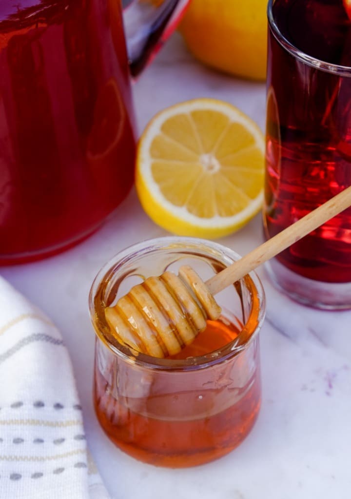 Honey in a small glass jar with a honey dipper. 