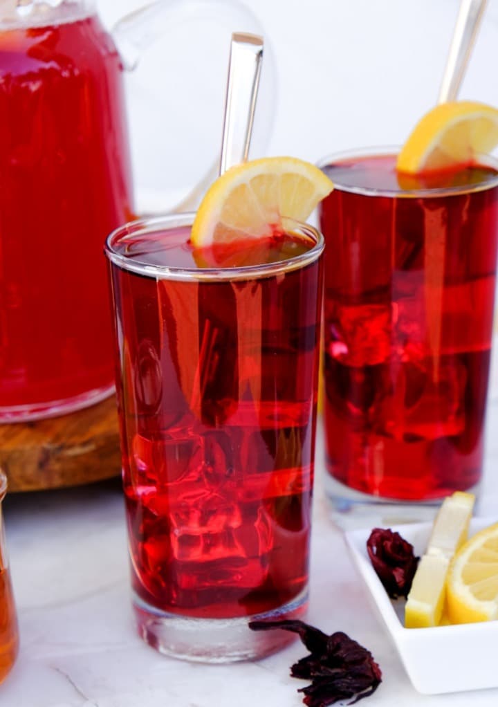 Hibiscus lemonade in a clear glass with lemon slice in the glass. 