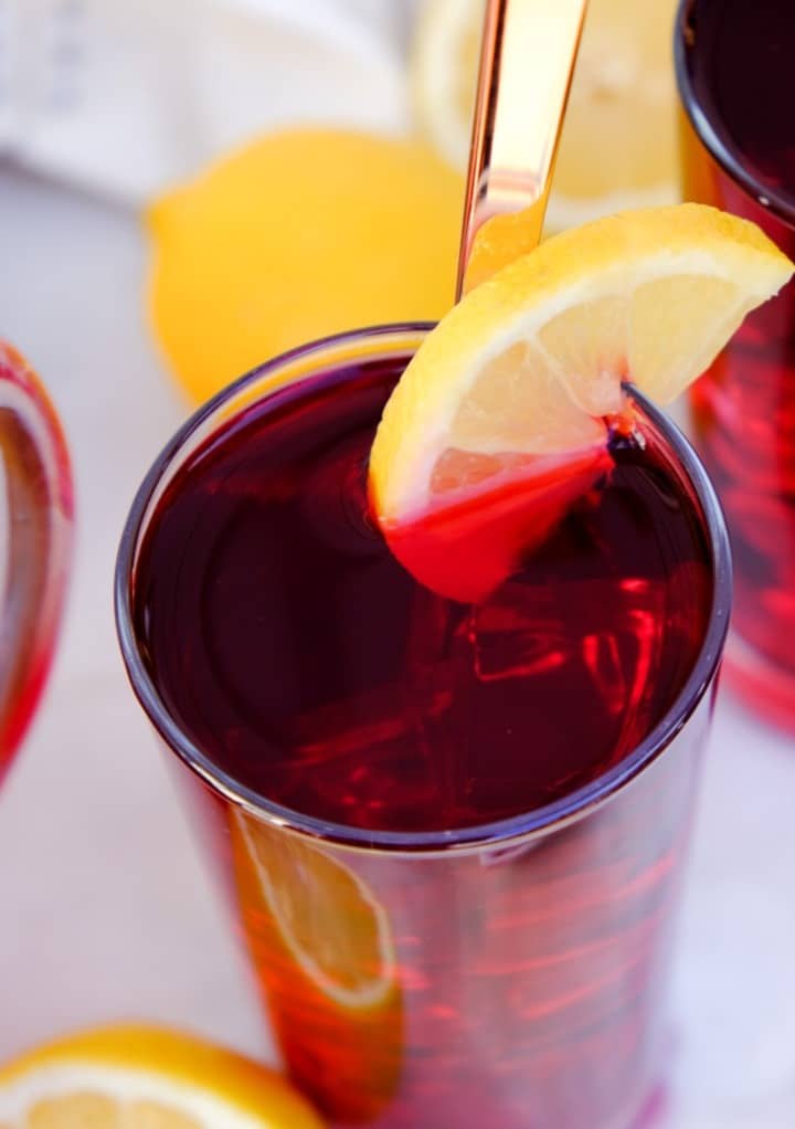 Hibiscus tea in a clear glass with a slice of lemon. 