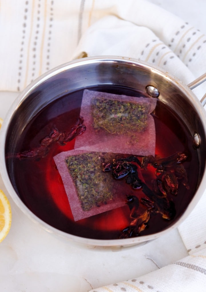 Steeping tea bags and dried flowers in a saucepan of water. 