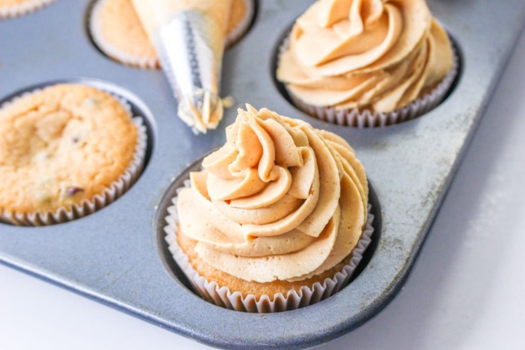 Peanut butter frosting piped on cupcakes. 