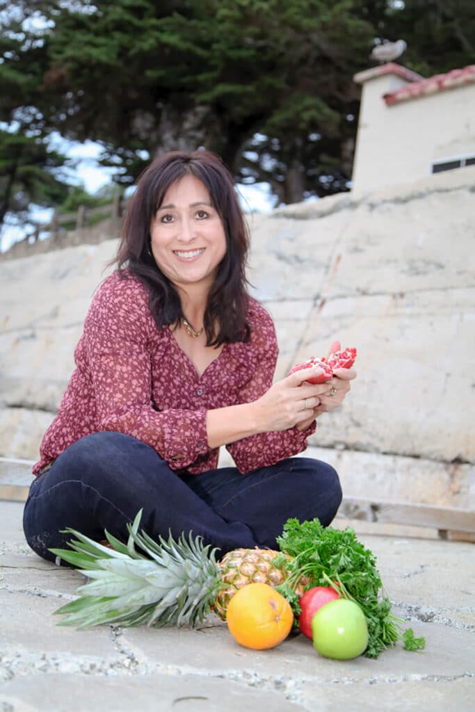 Photo of Sandra sitting on the floor with a bunch of fruits