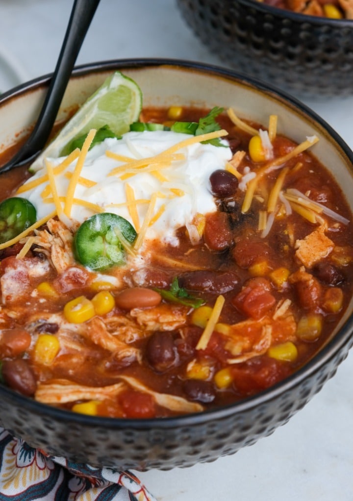 Sour cream and shredded cheese on a bowl of chicken taco soup.