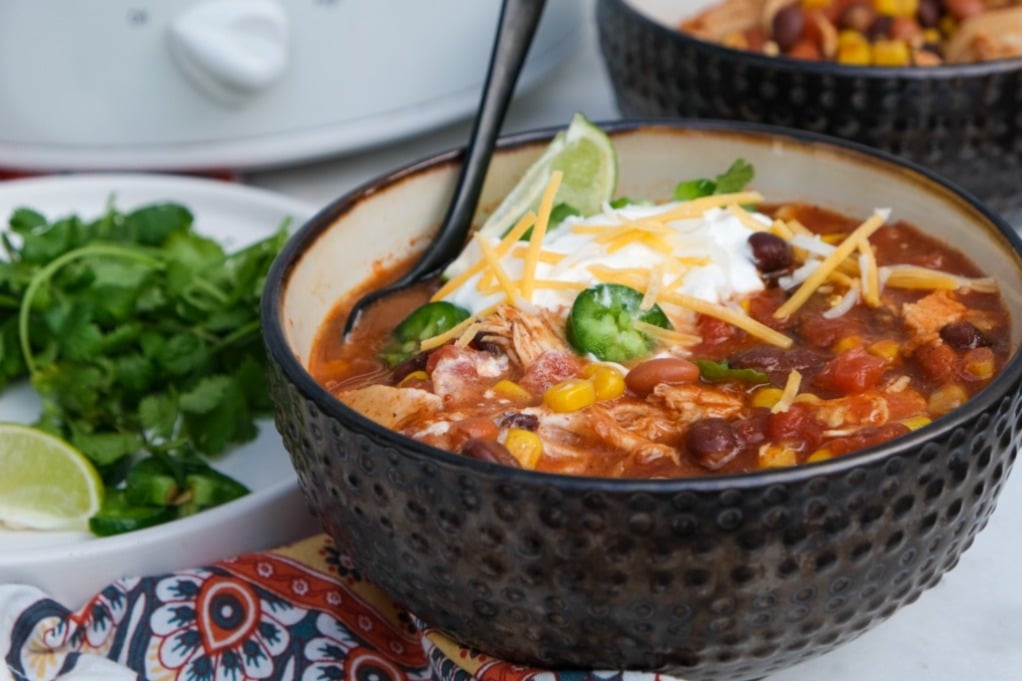 Slow cooker chicken taco soup in a serving bowl with a spoon ready to eat. 