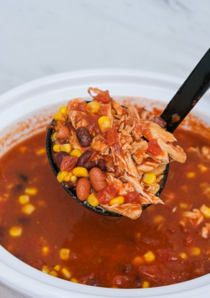 Ladle of chicken taco soup from a slow cooker.