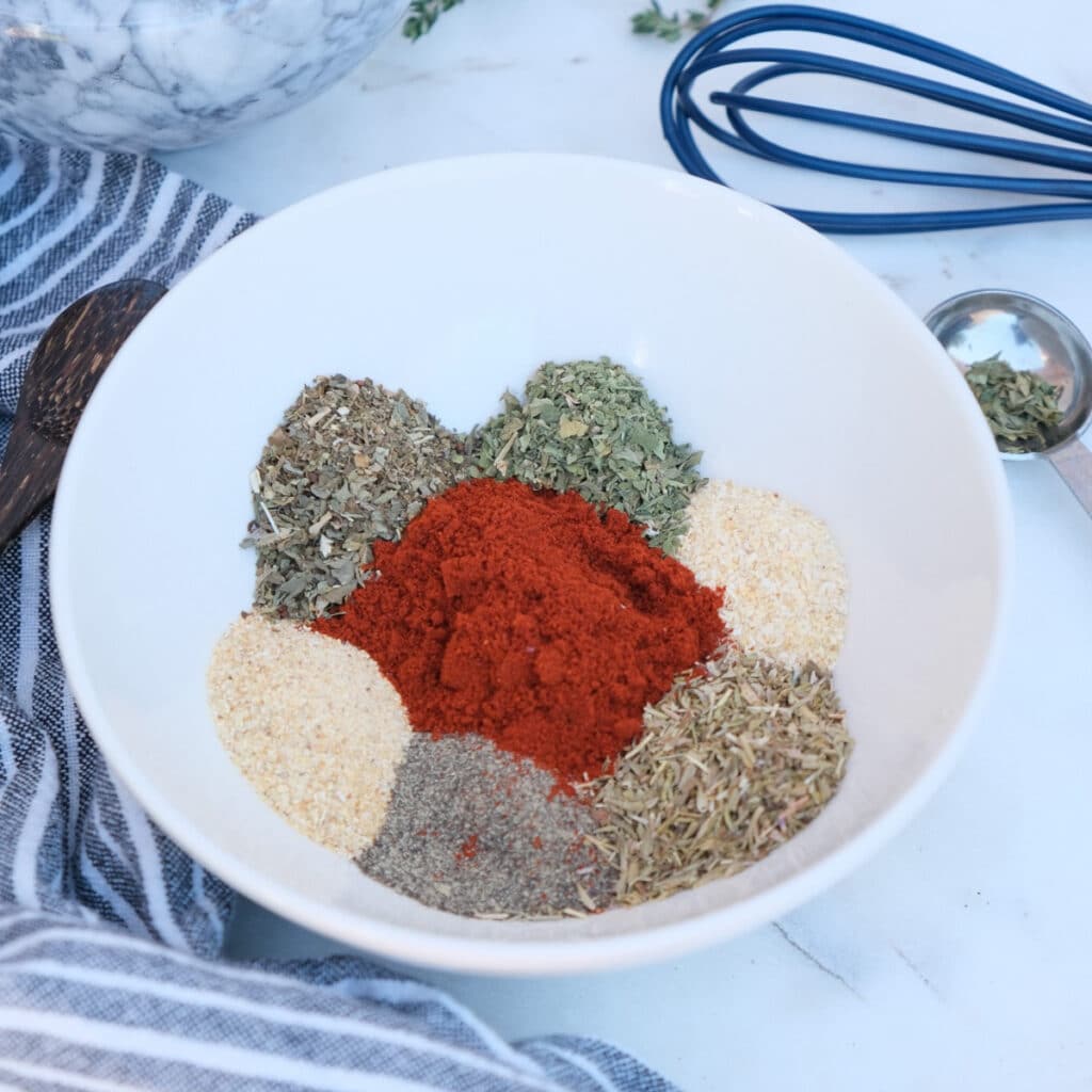 Herbs and spices in a small white mixing bowl for homemade easy steak seasoning mix recipe.