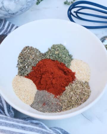 Herbs and spices in a small white mixing bowl for homemade easy steak seasoning mix recipe.