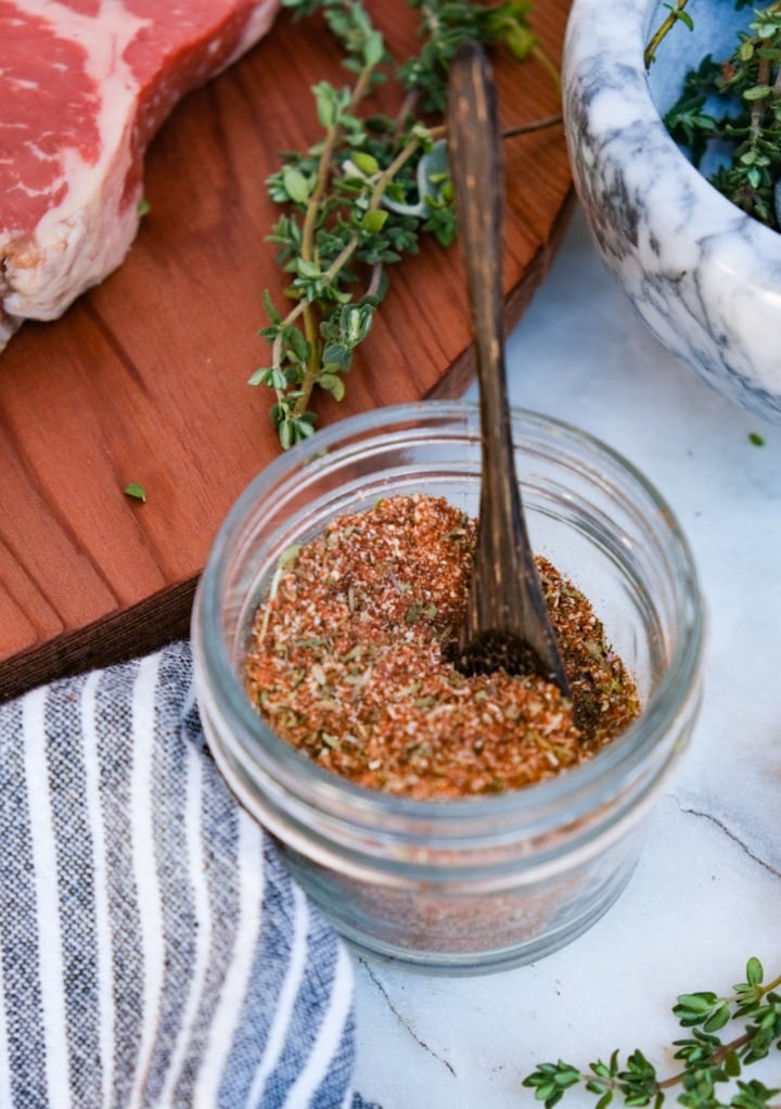 Steak seasoning spices in a small mason jar with a wooden spoon.