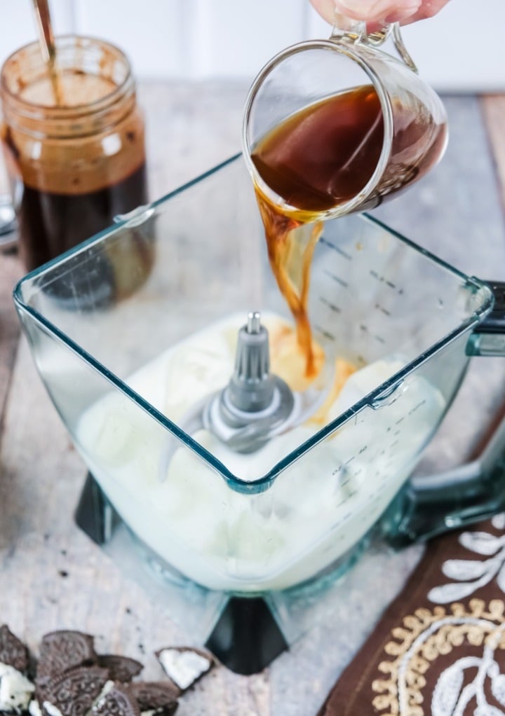 Pouring espresso in a blender with milk and ice. 