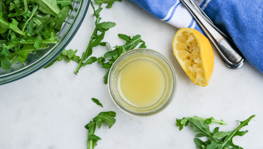 Lemon dressing in a small jar before adding to arugula salad. 