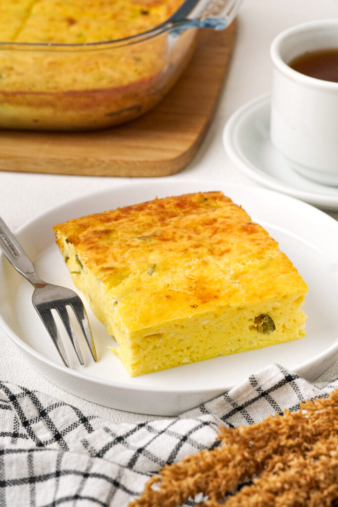 Slice of egg breakfast casserole on a white plate. 