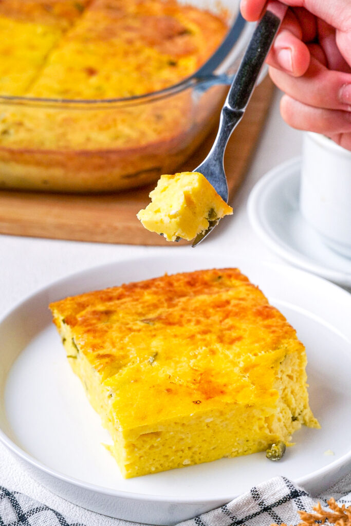 Forkful of green chile egg casserole on a white plate. 