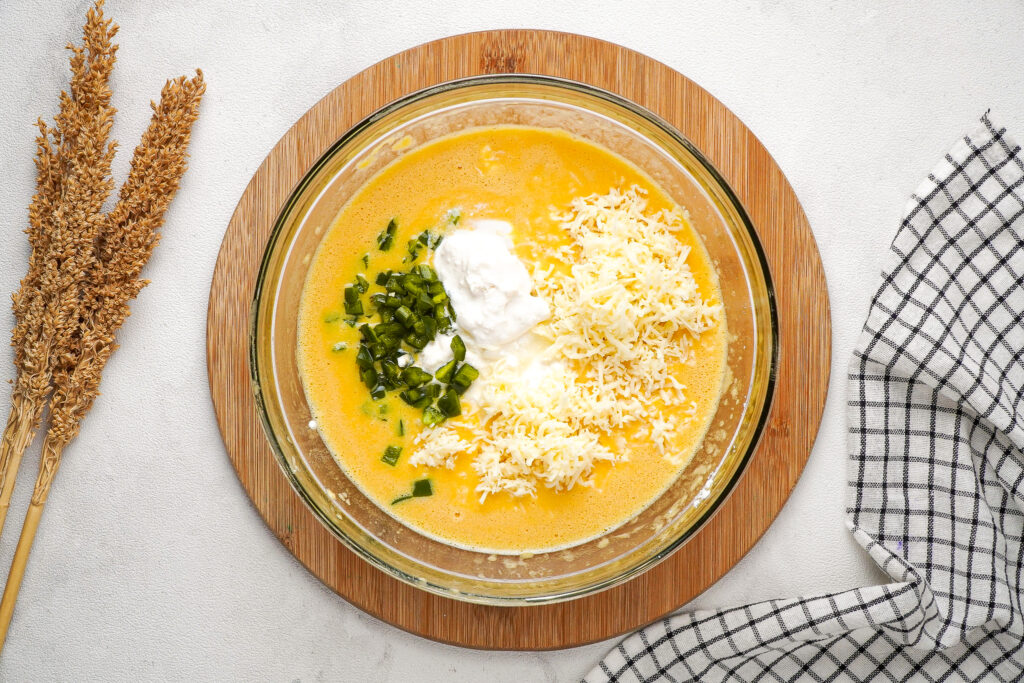 Egg mixture in a mixing bowl with cottage cheese and Monterey Jack cheese before mixing. 