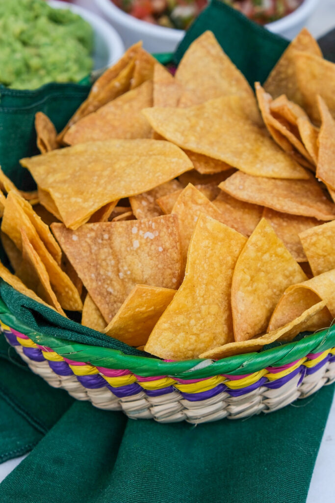 Homemade tortilla chips in a straw basket.