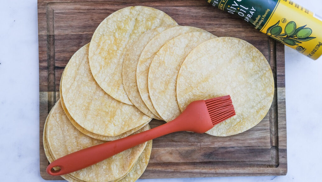 Coating corn tortillas with oil before baking or air frying. 