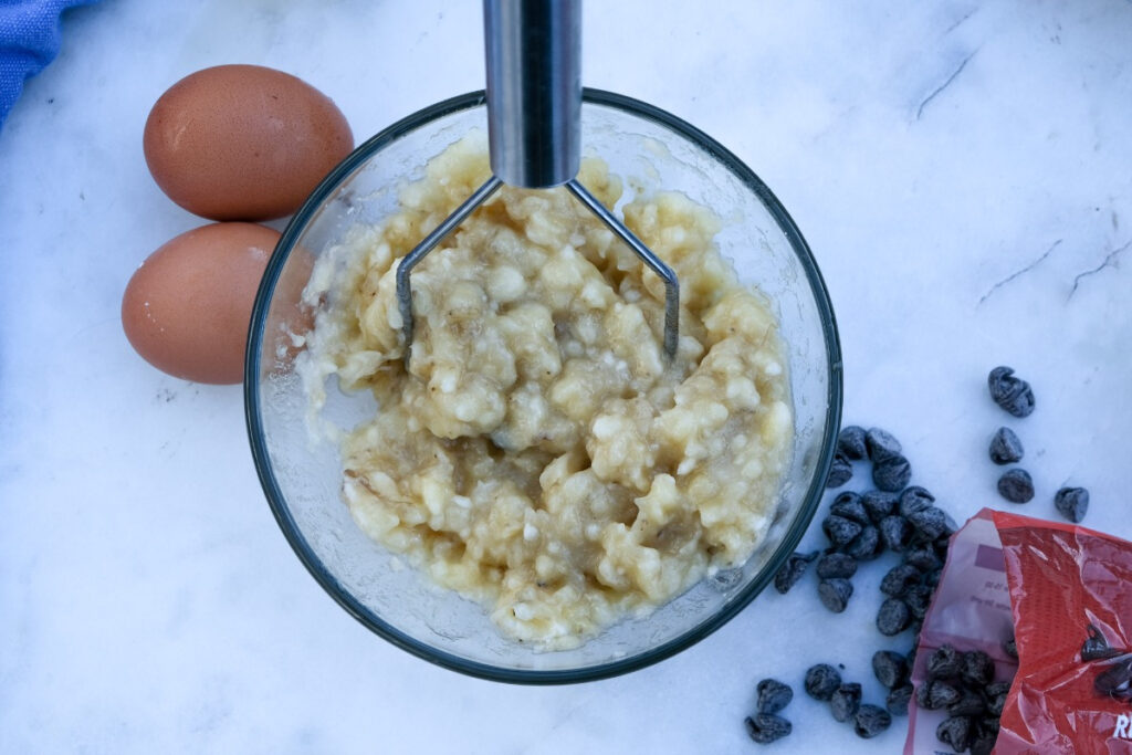 Mashed bananas in a clear mixing bowl. 