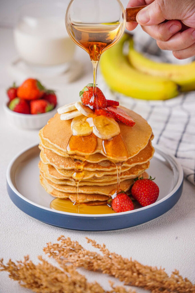 A stack of banana oatmeal pancakes with maple syrup.