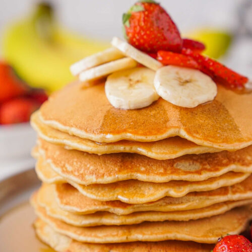 Large stack of banana oatmeal pancakes topped with sliced fresh bananas.