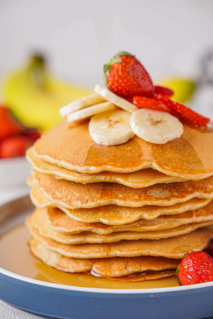 Large stack of banana oatmeal pancakes topped with sliced fresh bananas.