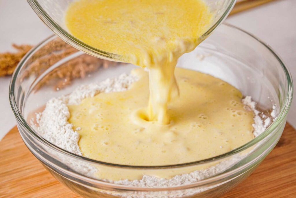 Adding wet ingredients into dry ingredients for homemade pancake batter. 