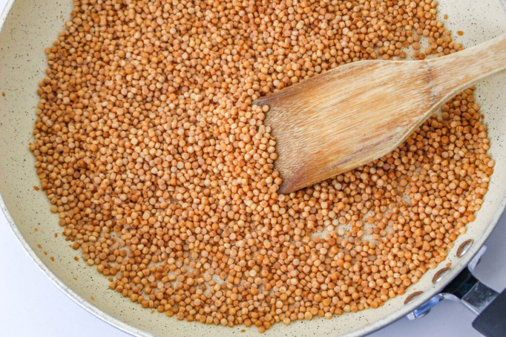 A large skillet with couscous browning. 