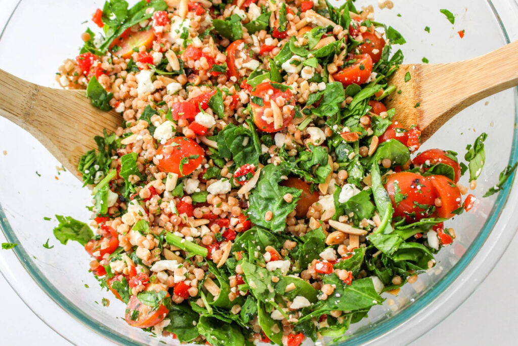 Israeli couscous with lemon dressing in a large clear mixing bowl. 