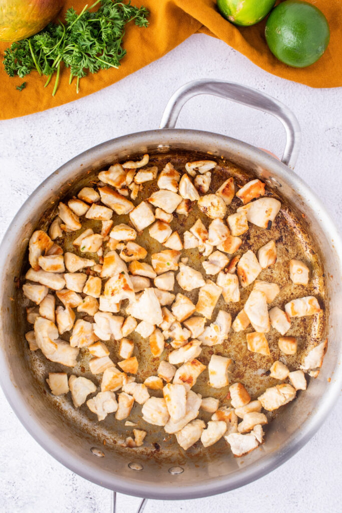 Diced chicken in a large skillet after browning. 
