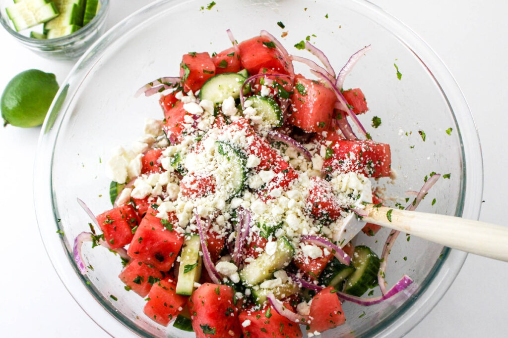 Feta cheese over watermelon salad before mixing ingredients together. 