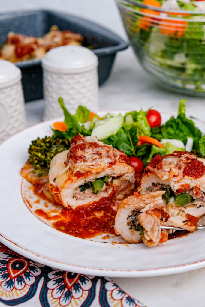 Chicken topped with marinara sauce with green salad on the side. 