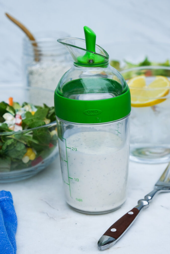 Keto ranch dressing in a salad dressing pourer with a green rim and spout. 