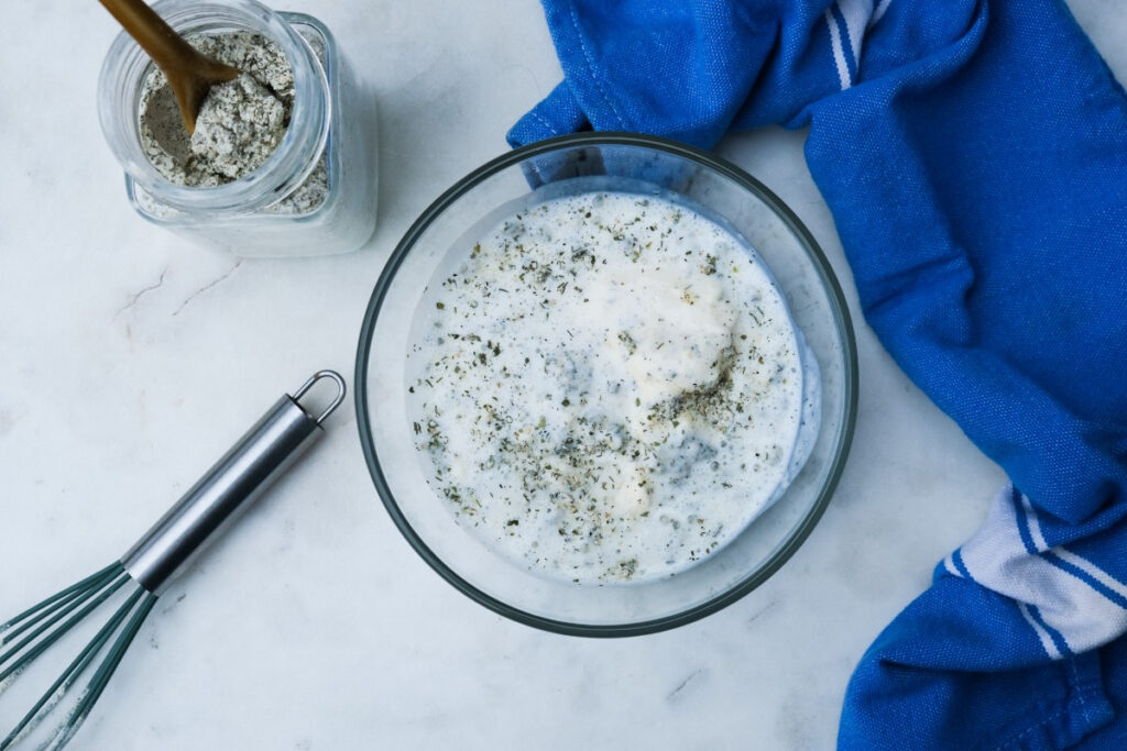 Homemade ranch dressing ingredients in a clear mixing bowl.